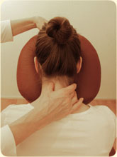 Een vrouw zit op een massage stoel en krijgt een hoof- en  nekmassage